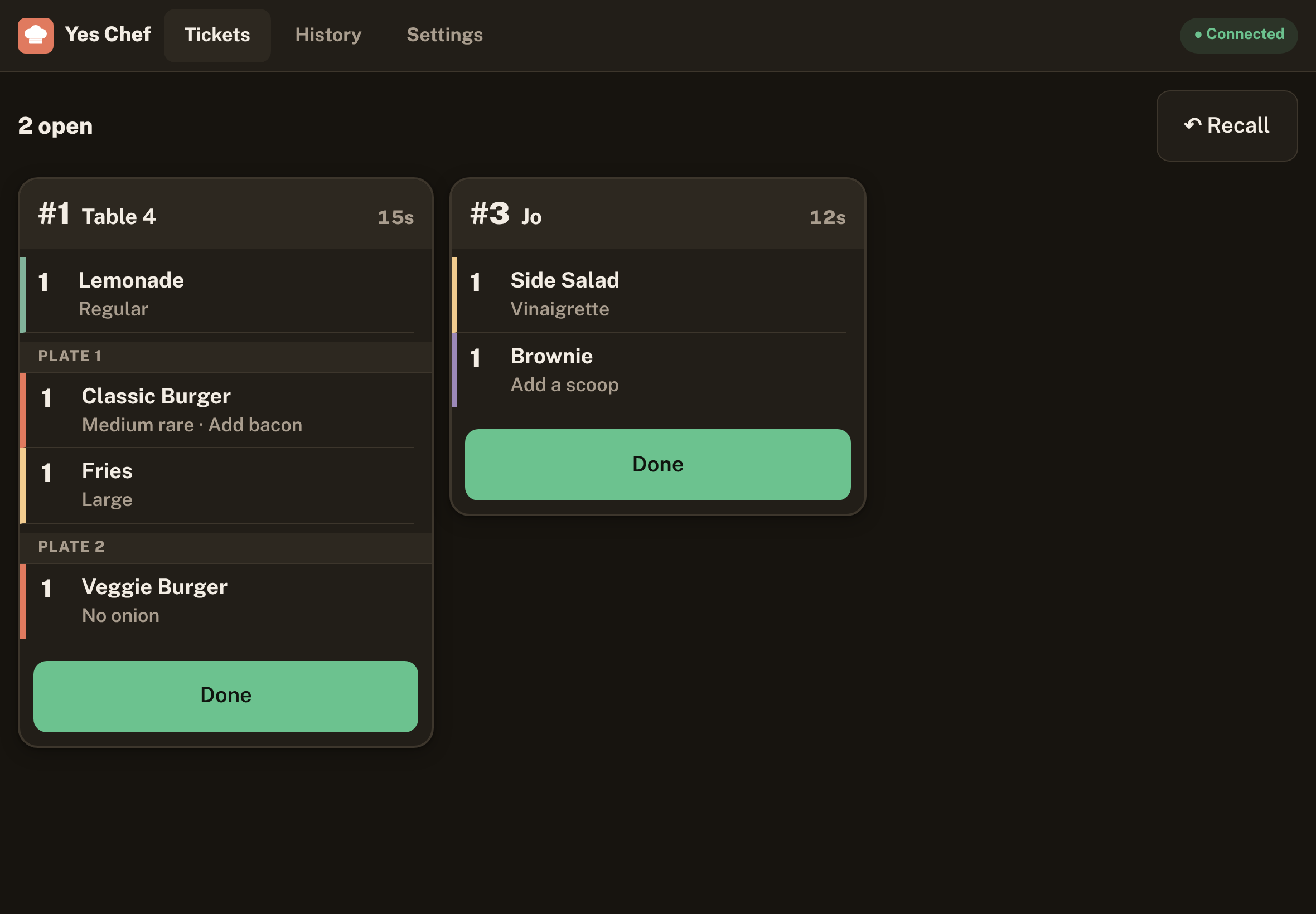 Kitchen screen in dark mode with two open tickets; Table 4 shows Lemonade, then Plate 1 with a Classic Burger and Fries, then Plate 2 with a Veggie Burger.
